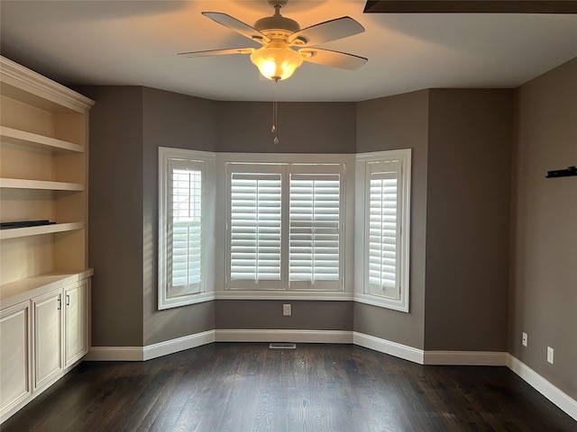 empty room with baseboards, dark wood-style flooring, and ceiling fan