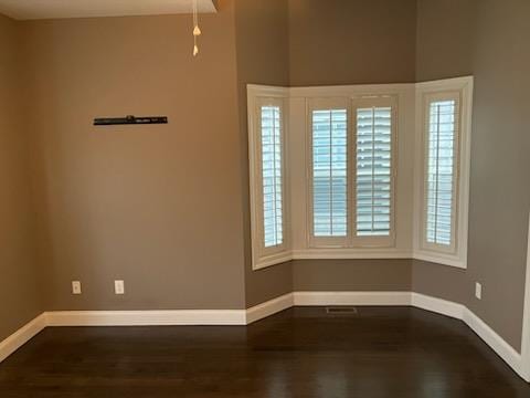 spare room with dark wood finished floors and baseboards