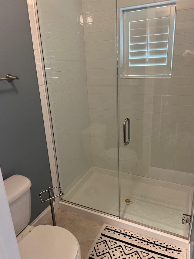 bathroom featuring toilet, baseboards, and a stall shower