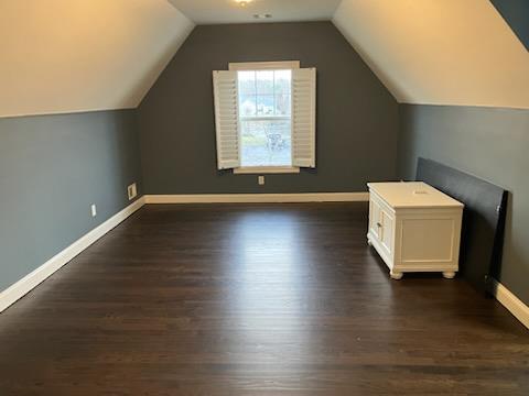 bonus room with dark wood-type flooring, baseboards, and lofted ceiling