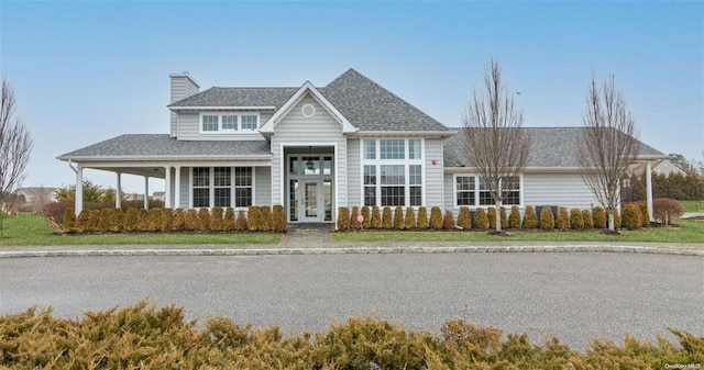 view of front of property featuring french doors, a chimney, and a shingled roof