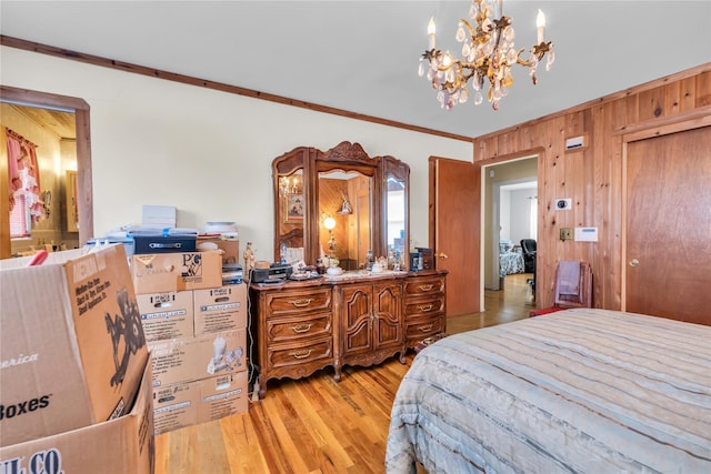 bedroom with crown molding, an inviting chandelier, wood finished floors, and wooden walls