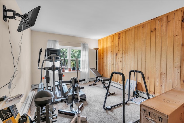 exercise area featuring wooden walls, a baseboard radiator, and carpet floors