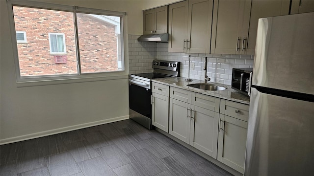 kitchen featuring under cabinet range hood, a sink, backsplash, stainless steel appliances, and baseboards