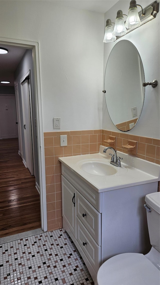 bathroom with vanity, a wainscoted wall, tile patterned flooring, tile walls, and toilet