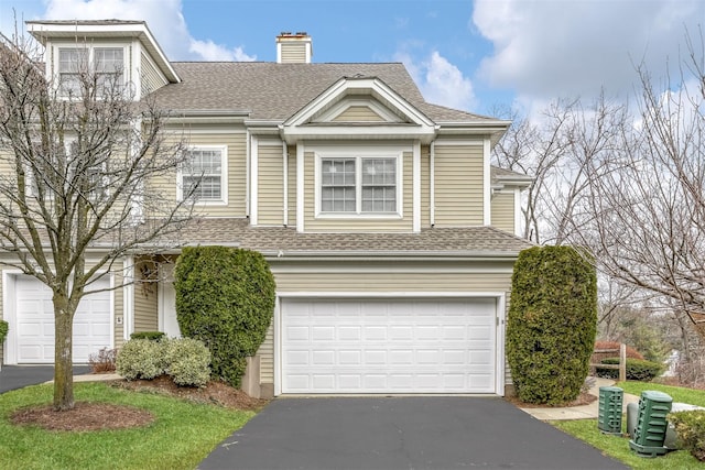 view of front of home featuring aphalt driveway, an attached garage, a chimney, and a shingled roof