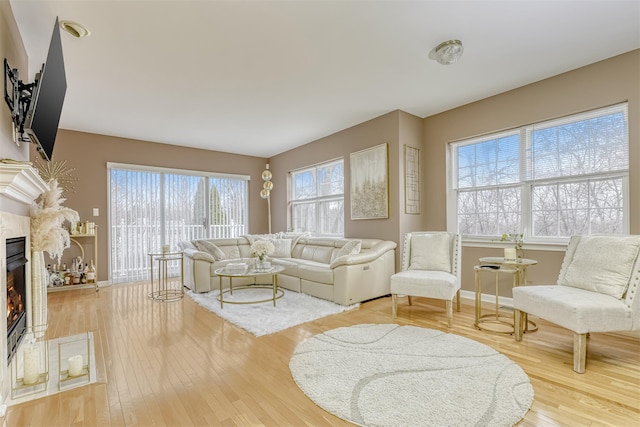 living area featuring light wood finished floors, a fireplace, and baseboards