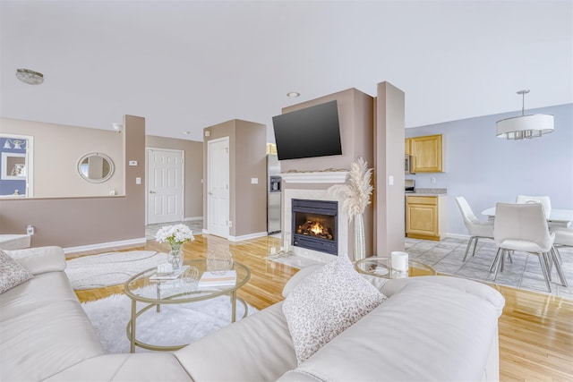 living room featuring a premium fireplace, baseboards, and light wood-style flooring