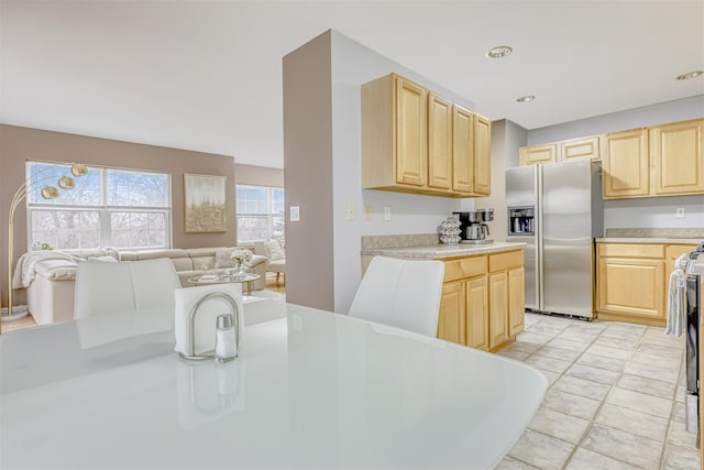 kitchen with light brown cabinets, light countertops, and stainless steel refrigerator with ice dispenser