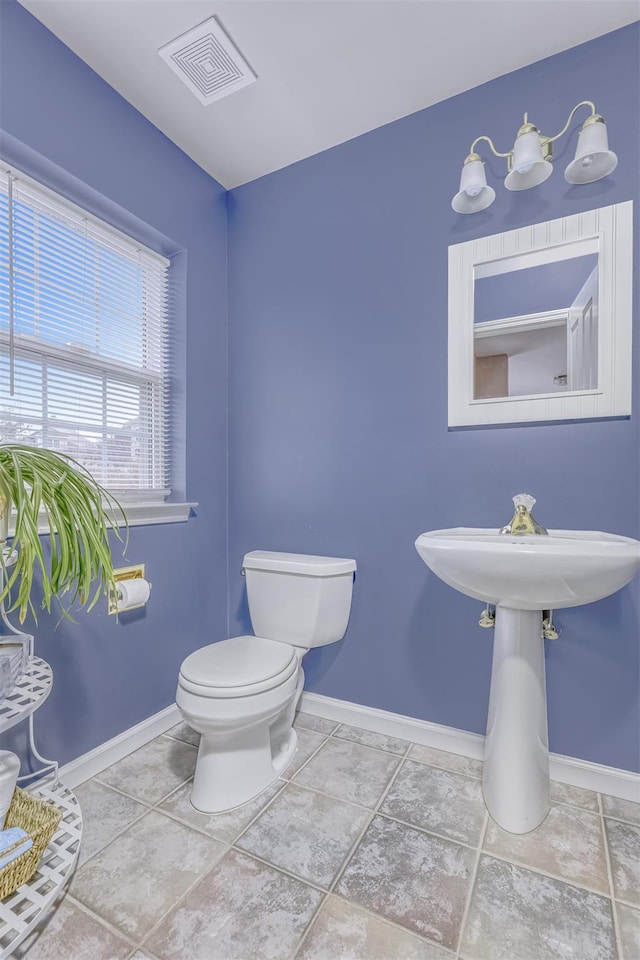 half bath with visible vents, baseboards, and toilet