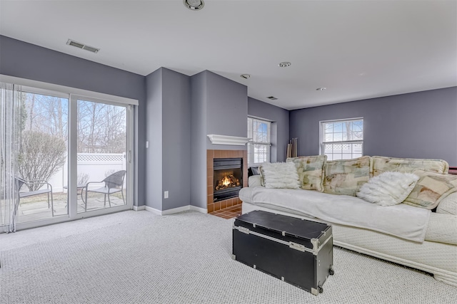 carpeted living area featuring visible vents, baseboards, and a fireplace