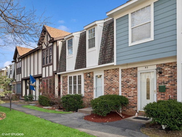 townhome / multi-family property featuring brick siding, mansard roof, and roof with shingles