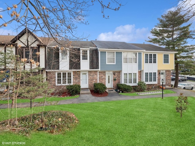 townhome / multi-family property with brick siding and a front yard