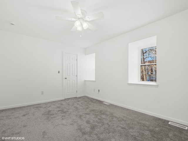 empty room with visible vents, carpet floors, baseboards, and a ceiling fan