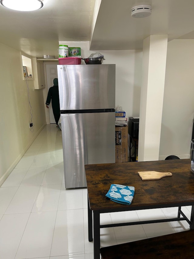 kitchen featuring light tile patterned floors, freestanding refrigerator, and baseboards