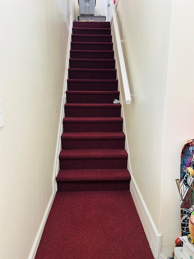 staircase featuring carpet and baseboards