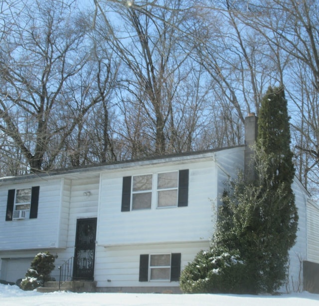 bi-level home featuring a garage and a chimney