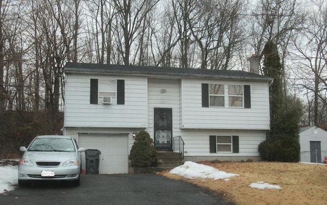 bi-level home featuring aphalt driveway, a chimney, and a garage