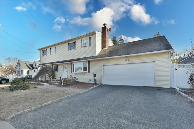 view of front of property with driveway, a gate, fence, an attached garage, and a chimney