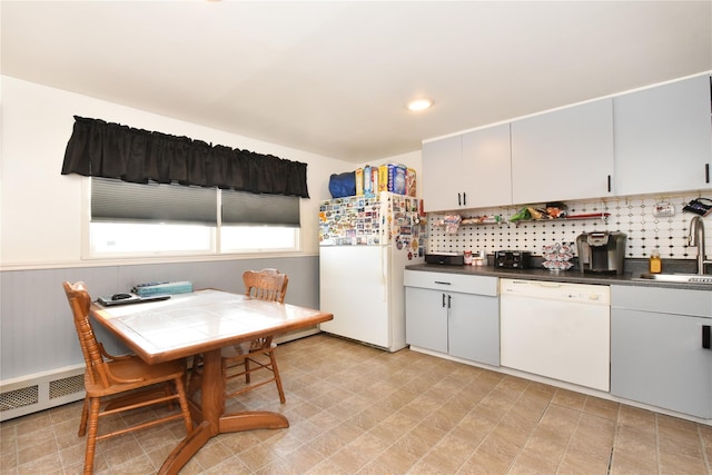 kitchen with dark countertops, tasteful backsplash, wainscoting, white appliances, and a sink