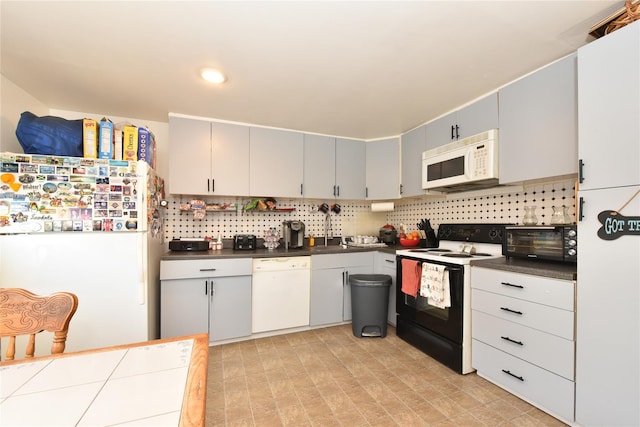 kitchen featuring dark countertops, backsplash, a toaster, white appliances, and a sink