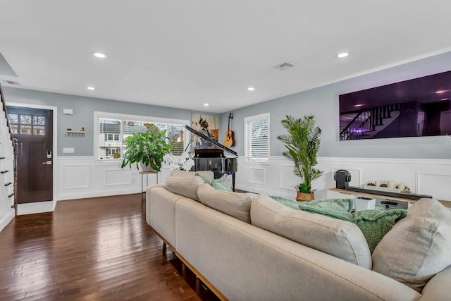 living area featuring visible vents, recessed lighting, hardwood / wood-style flooring, wainscoting, and a decorative wall