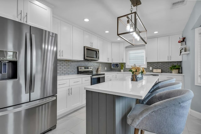 kitchen featuring a breakfast bar area, visible vents, light countertops, appliances with stainless steel finishes, and tasteful backsplash