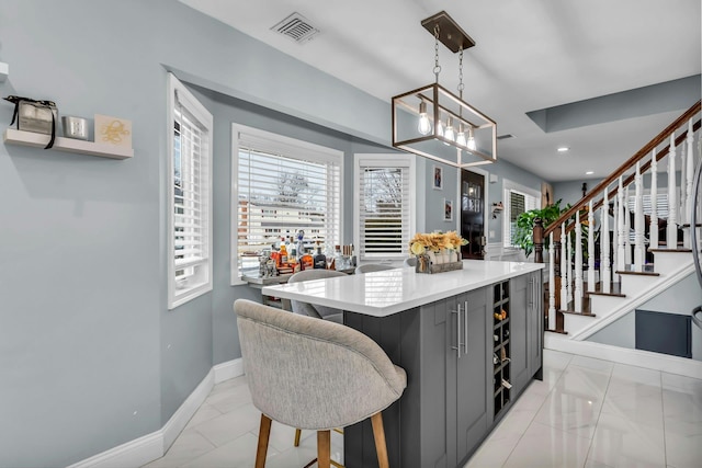 kitchen with visible vents, a center island, baseboards, decorative light fixtures, and gray cabinets