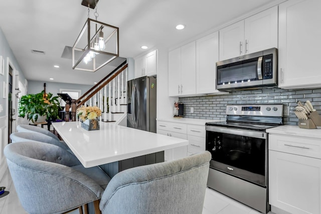 kitchen featuring visible vents, a breakfast bar, light countertops, appliances with stainless steel finishes, and white cabinetry