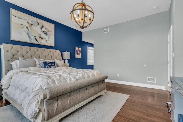 bedroom featuring visible vents, baseboards, a notable chandelier, and wood finished floors