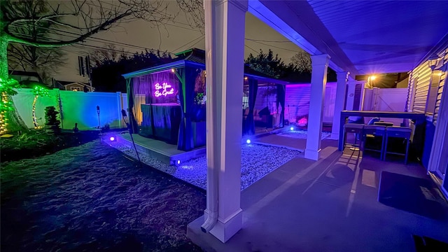 patio at night featuring a fenced backyard