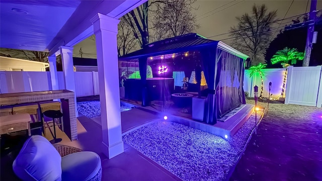 patio at night featuring a fenced backyard