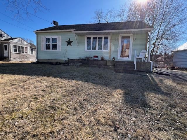 view of front of house with a front yard and a shingled roof