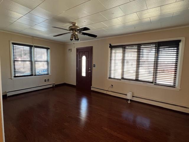 foyer entrance featuring a healthy amount of sunlight, wood finished floors, ornamental molding, and a baseboard radiator