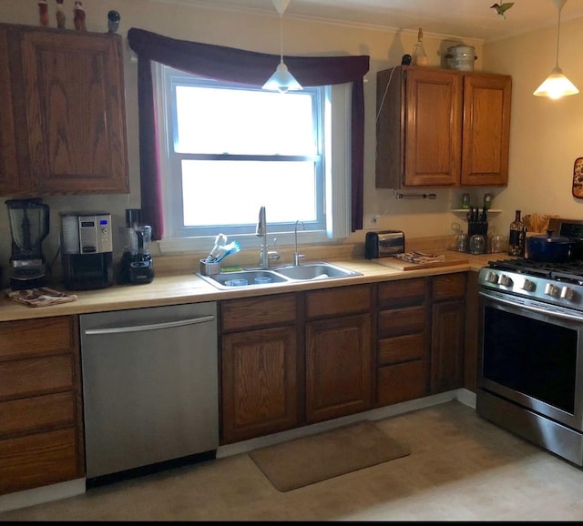 kitchen with a sink, hanging light fixtures, light countertops, appliances with stainless steel finishes, and brown cabinets