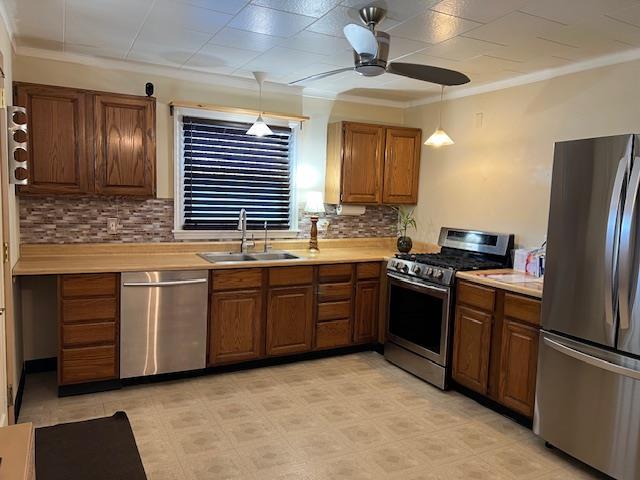 kitchen with light countertops, brown cabinetry, appliances with stainless steel finishes, and a sink