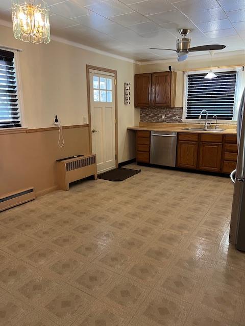 kitchen featuring brown cabinetry, radiator heating unit, a sink, stainless steel appliances, and light countertops