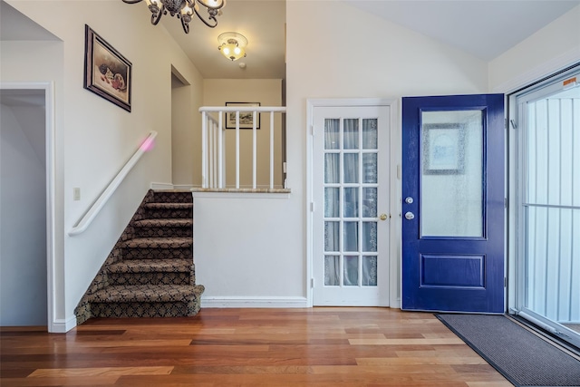 entryway with baseboards, a chandelier, stairway, vaulted ceiling, and wood finished floors