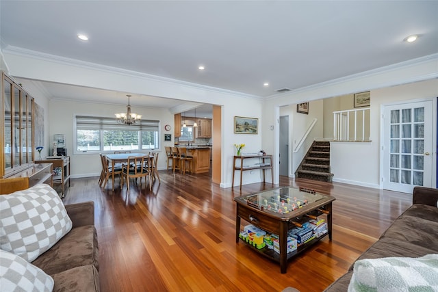 living area featuring stairs, ornamental molding, dark wood-style floors, and a chandelier