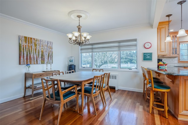 dining room with ornamental molding, wood finished floors, and a chandelier