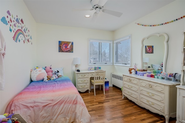 bedroom with light wood-style floors, radiator, and a ceiling fan