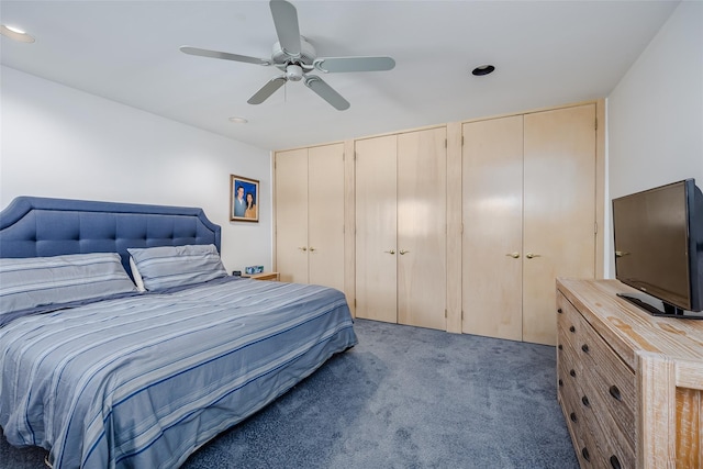 carpeted bedroom with a ceiling fan and two closets