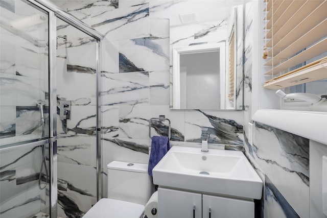 bathroom featuring visible vents, toilet, a marble finish shower, tile walls, and vanity