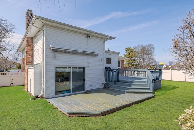 back of property featuring a yard, a fenced backyard, a chimney, and a deck