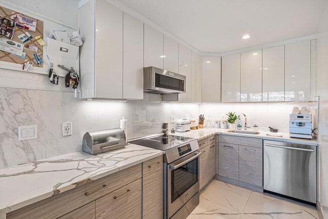 kitchen featuring marble finish floor, stainless steel appliances, modern cabinets, and a sink