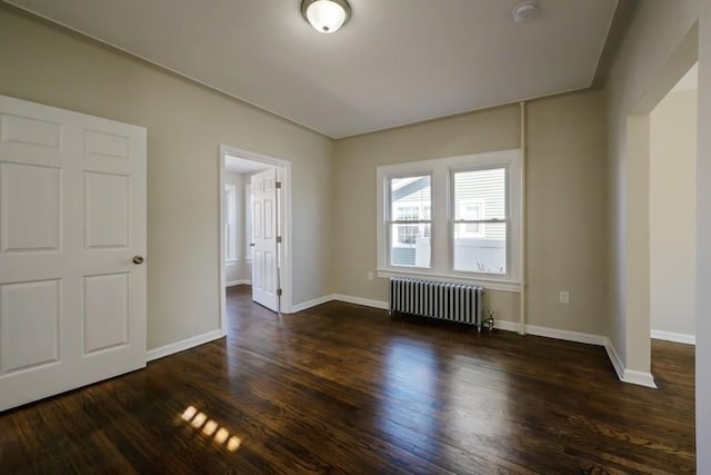 unfurnished bedroom featuring radiator, baseboards, and dark wood-style flooring