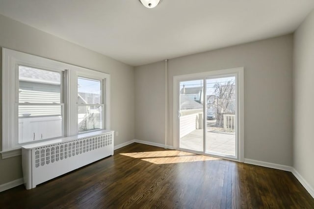 empty room featuring baseboards, radiator, and wood finished floors