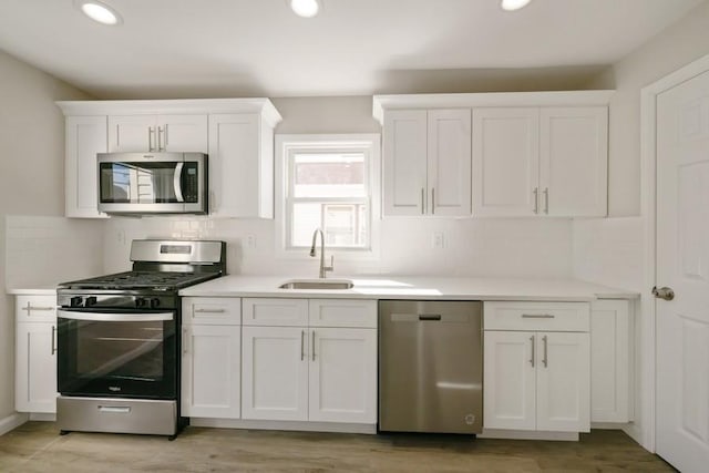 kitchen featuring a sink, appliances with stainless steel finishes, white cabinets, and light countertops