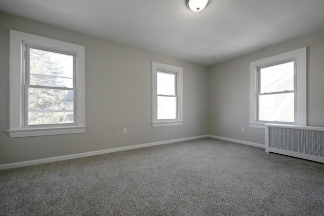 carpeted empty room featuring radiator heating unit and baseboards