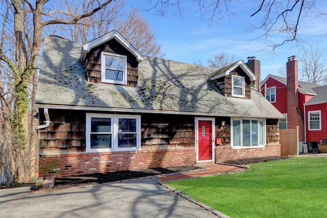 cape cod house featuring a chimney and a front yard